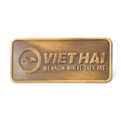 Custom embossed brass label attached to wooden furniture surface