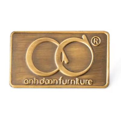 Custom embossed brass label attached to wooden furniture surface
