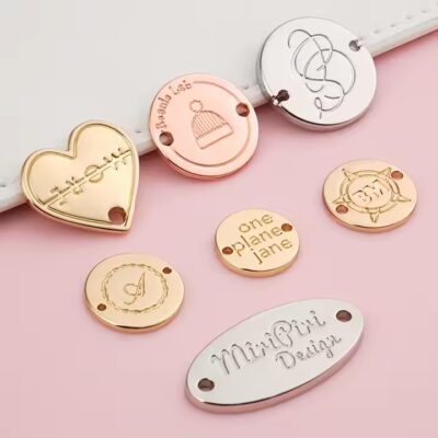 Custom laser engraved metal tag attached to clothing and bags, showing clear personalized branding