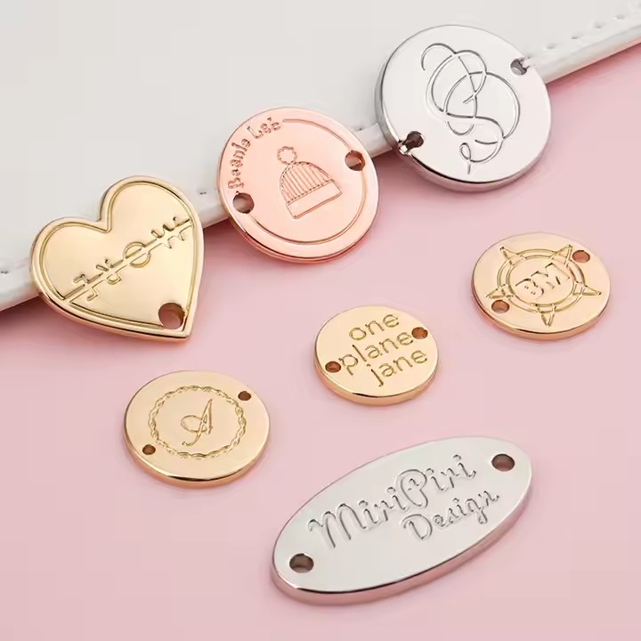 Custom laser engraved metal tag attached to clothing and bags, showing clear personalized branding